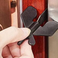 a person is opening a door with a black handle and an iron latch on it