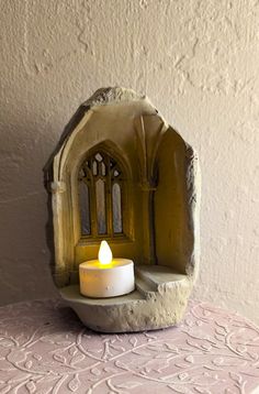 a lit candle sitting on top of a table next to a small arch shaped like a door