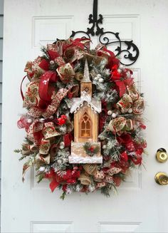 a christmas wreath hanging on the front door with a birdhouse and bells attached to it