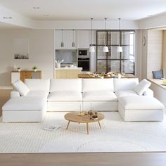 a large white sectional couch in a living room next to a kitchen and dining area