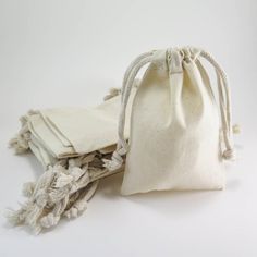 two white bags sitting next to each other on top of a table and one bag is filled with cloth