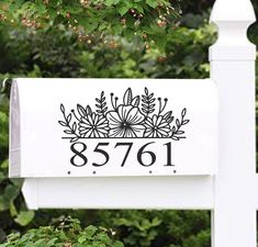 a white mailbox sitting next to a lush green forest