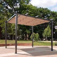 an empty park area with a canopy and street lights in the background