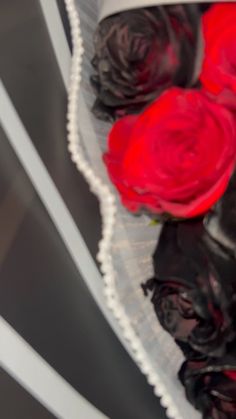 red roses are in a white vase on a table with black paper doilys