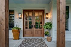 a front door with potted plants on the side and an entrance mat in front