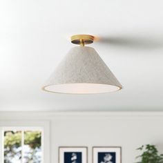 a living room with white walls and pictures on the wall, including a ceiling light