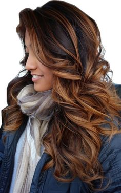 a woman with long, wavy hair wearing a blue jacket and scarf is smiling at the camera