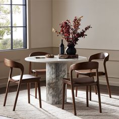 a round table with four chairs around it and a vase filled with flowers on top