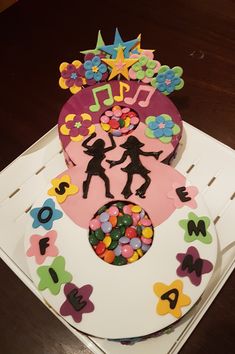 the cake is decorated with children's silhouettes and flowers on top of it