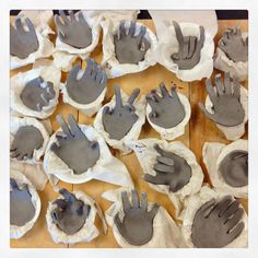 many hands are made out of clay on a wooden table with white paper around them