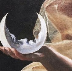 a close up of a person holding an object in their hand with the moon visible