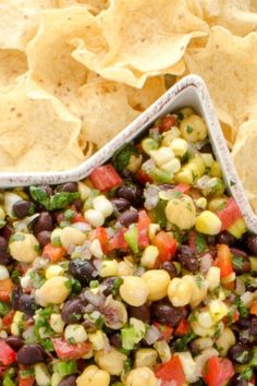 a bowl filled with black beans and corn next to tortilla chips