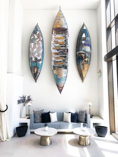 three surfboards mounted to the wall above a couch in a room with white walls