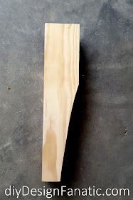 an unfinished piece of wood sitting on top of a cement floor next to a knife