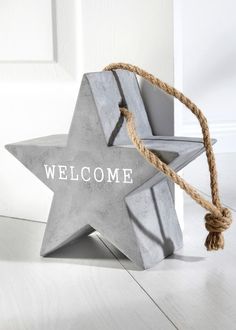 a concrete star with the word welcome hanging from it's side on a white wooden floor