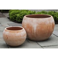 two large clay pots sitting on top of a stone walkway