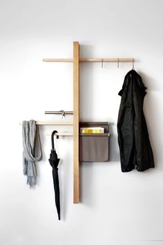 a coat rack with an umbrella and other items hanging on the wall next to it