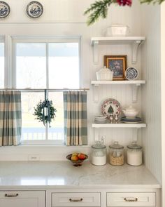 a kitchen with white cupboards and shelves filled with dishes on top of each other