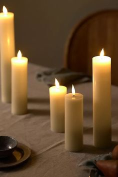 several lit candles sitting on top of a table next to a plate and spoons