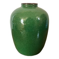 a large green vase sitting on top of a white table