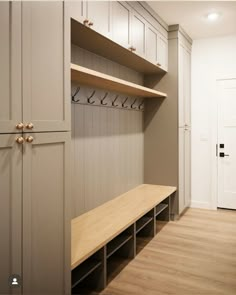 an empty walk - in closet with wooden shelves and coat hooks on the wall,