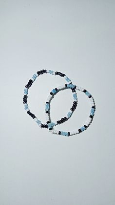 two bracelets with blue and black beads are on a white surface, next to each other