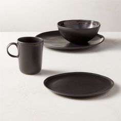 two black cups and saucers on a white table