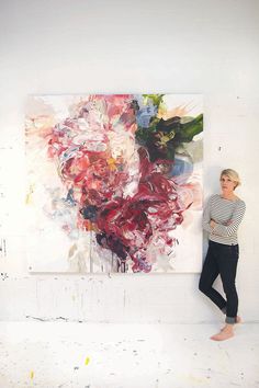 a woman standing next to a large painting