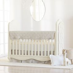 a white crib in a room with a mirror on the wall and other furniture