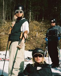 two skiers and a snowboarder standing in the snow with their gear on