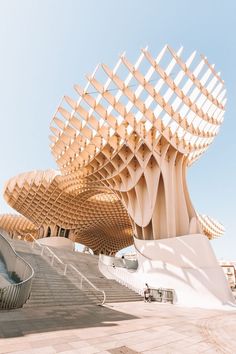 a large wooden structure sitting on top of a cement floor next to a building with stairs and railings