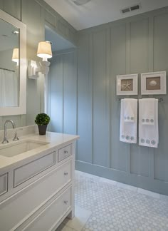 a bathroom with blue walls and white counter tops, two towels hanging on the wall