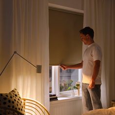 a man standing in front of a window looking out at the street outside his bedroom