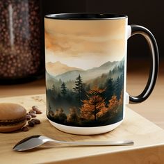 a coffee mug sitting on top of a wooden table next to a spoon and cup