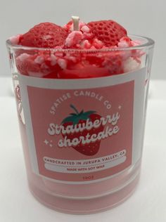 strawberry shortcake scented candle in glass container on white table with red and pink candies