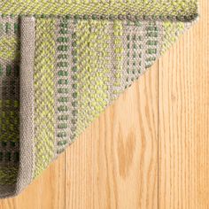 a green and gray rug on top of a wooden floor