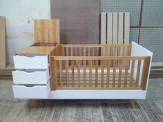 a baby crib with two drawers and a dresser next to it on the floor