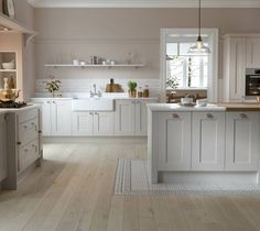 a large kitchen with white cabinets and wooden floors