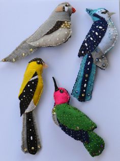 four small birds made out of fabric and sequins on a white table top