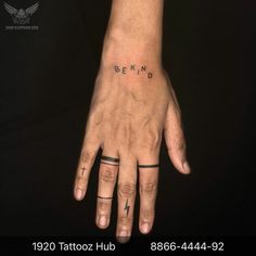 a person with two tattoos on their fingers and the words behind them are written in black ink