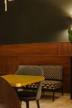 a table and chairs in a room with wood paneling on the wall behind them