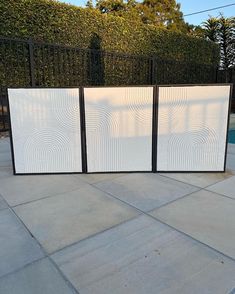 a white screen sitting on top of a cement floor next to a pool and fence