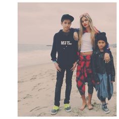 two boys and a girl standing on the beach