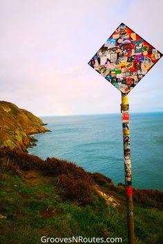 a street sign covered in stickers on the side of a hill by the ocean