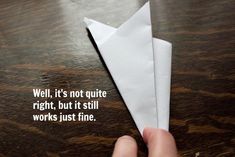 a person holding a paper airplane on top of a wooden table next to a quote