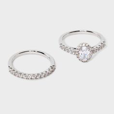 two silver rings with white stones on each side and one has a heart shaped diamond in the middle