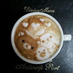 a cappuccino with hearts in it on a black table next to a menu