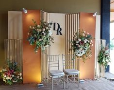 two chairs sitting next to each other in front of a wall with flowers on it