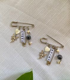 three different types of earrings sitting on top of a white cloth next to a green plant