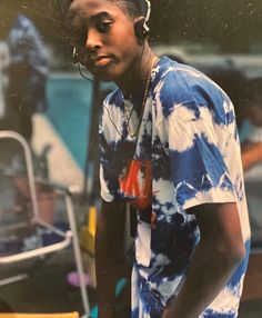 a man with headphones on standing in front of a microphone and wearing a tie dye shirt